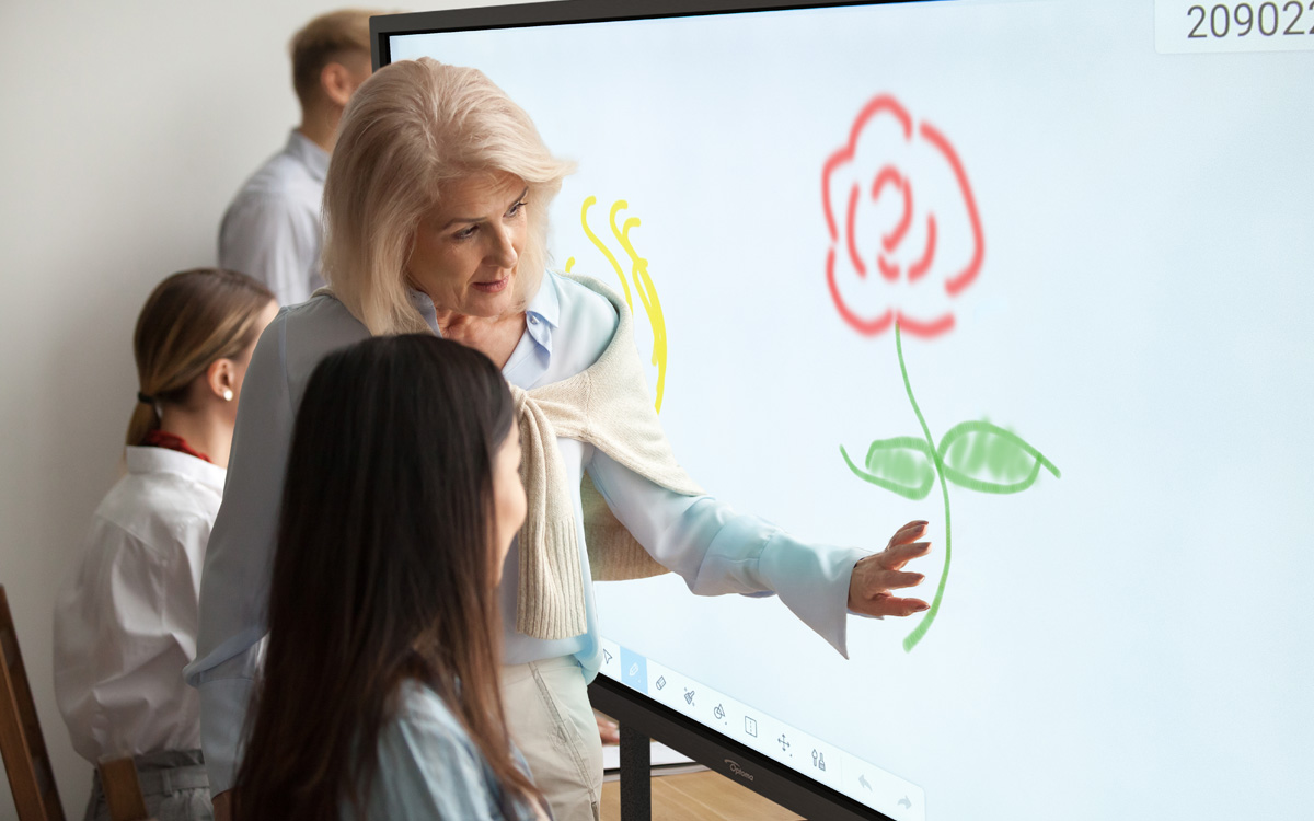Eine Lehrerin und eine Schülerin stehen vor einem interaktiven Touch Display.