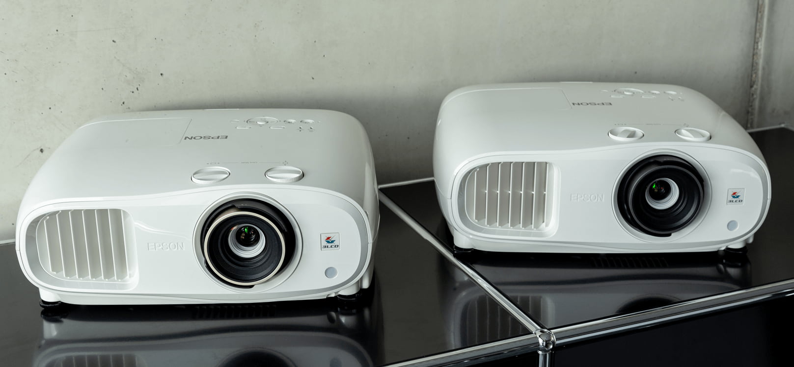 Epson EH-tw7000 und Epson eh-tw7100 Beamer auf einem schwarzen Sideboard