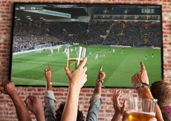 Leinwand auf dem ein Fußballspiel übertragen wirdin einer Gaststätte mit jubelnden Fans