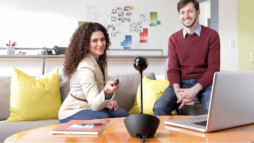 Büro mit einem Mann und einer Frau die vor der logitech Konferenzkamera sitzen