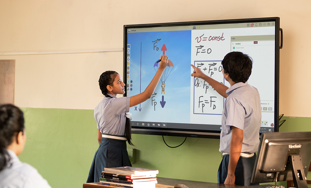 Zwei Schüler in Schuluniformen interagieren mit einer digitalen Tafel, die physikalische Formeln und Diagramme zum Thema Kräfte zeigt, während ihre Mitschüler zuschauen.