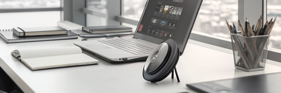 Freisprecheinrichtung Jabra Freisprecheinrichtung die auf einem Schreibtisch vor einem Laptop steht