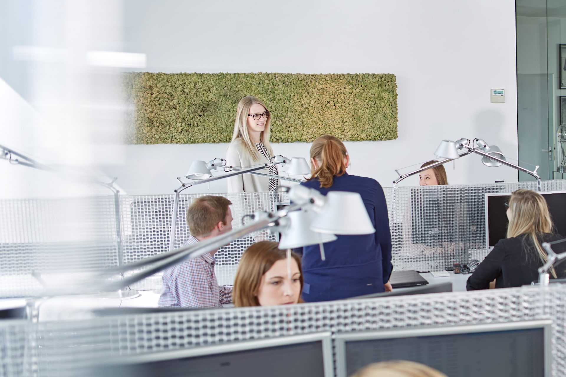 Erkennbar sind 5 Personen, die in einem Büro arbeiten. 