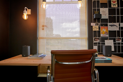 Büro mit einem Schreibtisch, auf dem rechts und links ein Denon Home 150 platziert ist